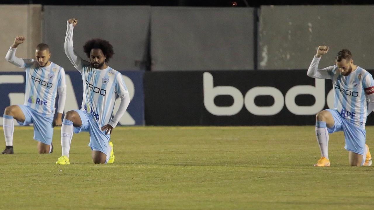 Jogadores do Londrina se ajoelham no gramado antes do jogo contra o Confiança