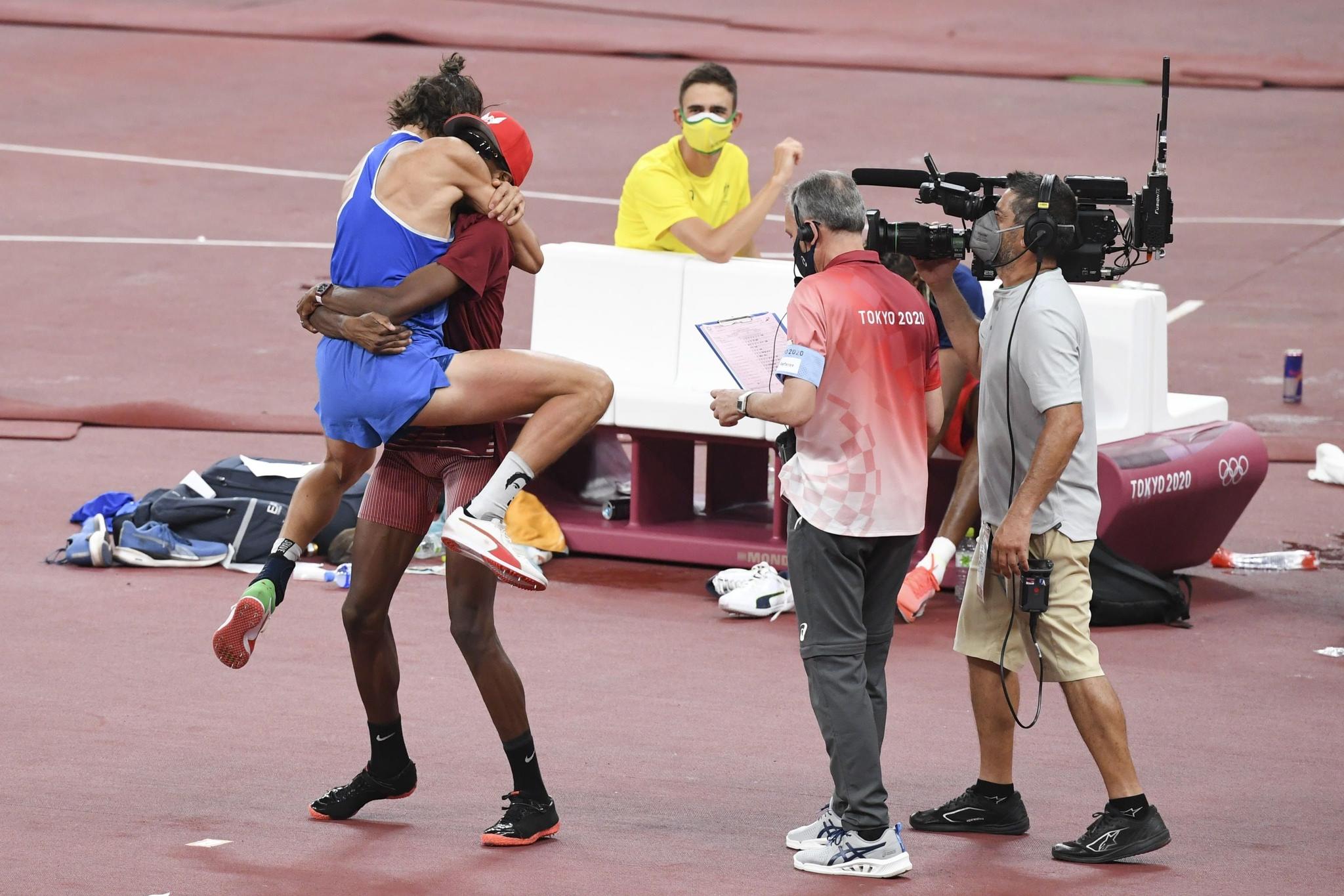 O italiano Gianmarco Tamberi (de azul) e o catari Mutaz Essa Barshim (de cor vinho) se abraçam depois de concordarem em dividir o ouro do salto em altura nos Jogos Olímpicos de Tóquio.