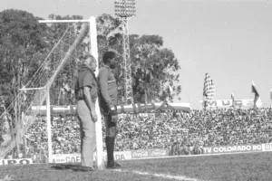 Atletiba de 1974. Jairo ouve instruções. Ao fundo, torcida coxa abarrota a reta do relógio da Vila Capanema. 